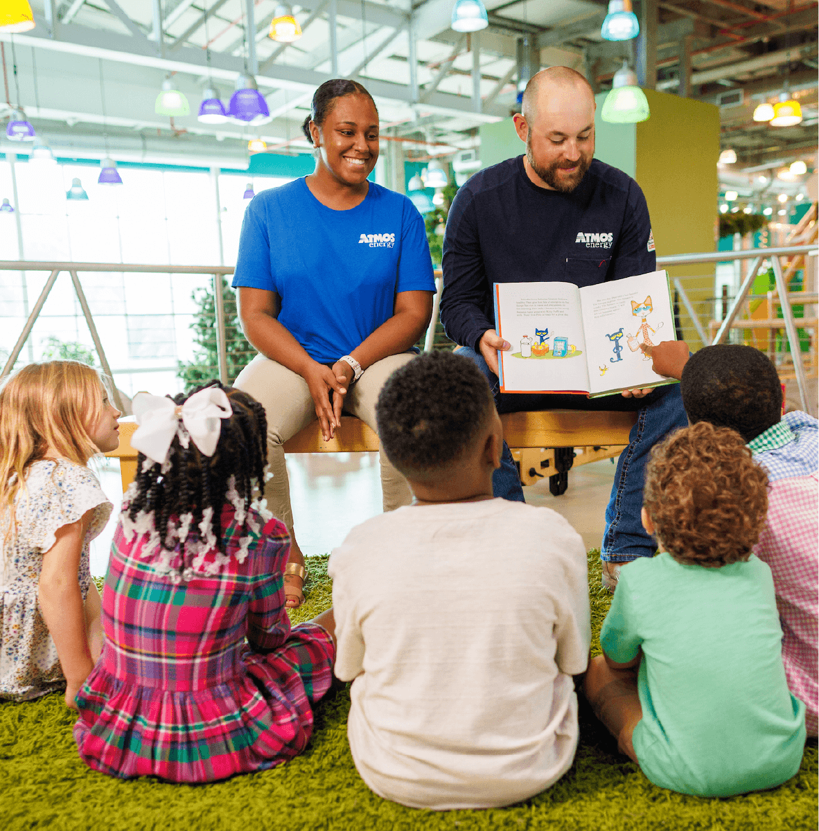 Fueling Safe and Thriving Communities in Mississippi Children sitting on a rug looking at a woman and man reading a book
